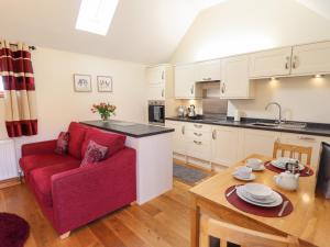uma cozinha e sala de estar com um sofá vermelho e uma mesa em The Stables em Louth
