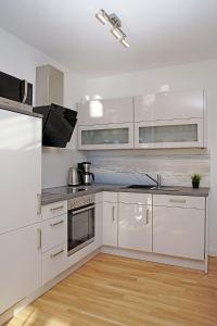 a kitchen with white cabinets and a stove top oven at Haus Yachthafen 4 in Cuxhaven