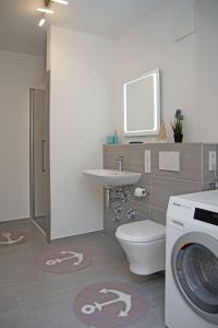 a bathroom with a toilet and a sink and a washing machine at Haus Yachthafen 4 in Cuxhaven