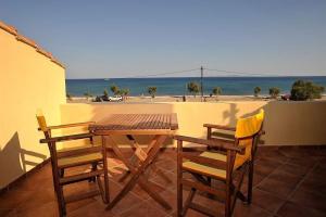 un tavolo in legno e sedie su un balcone con vista sulla spiaggia di Βιλλα Βεατρικη/ villa Beatrice a Pythagóreion