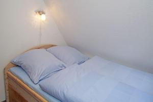クックスハーフェンにあるMuschelsucherのベッド1台(枕2つ付)、壁にライトが備わります。