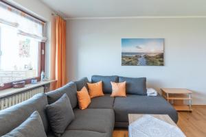 ein Wohnzimmer mit einem grauen Sofa und orangefarbenen Kissen in der Unterkunft Am Sahlenburger Strand Wohnung 8 in Cuxhaven
