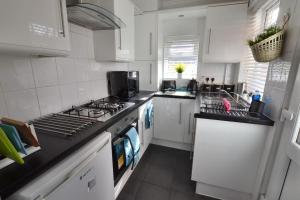 a kitchen with white cabinets and a stove top oven at Church View in Quorndon