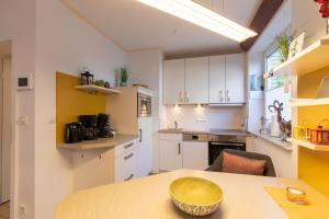 a kitchen with white cabinets and a yellow bowl on a table at Residenz Meeresbrandung, Whg 39 in Duhnen