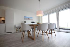 a dining room with a table and white chairs at Quartier Hohe Geest _ Wohnung Meer in Cuxhaven