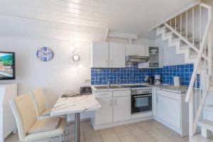 uma cozinha com armários brancos e uma parede de azulejos azuis em Haus Seewind Wohnung 2 em Cuxhaven