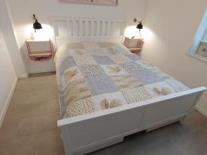 ein weißes Bett mit einer Decke im Schlafzimmer in der Unterkunft Ferienwohnung Meeresbrise in Norden