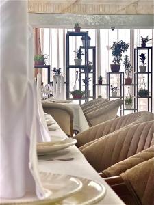 a dining room with tables and chairs and plants at Mir Luxe Plaza in Tashkent