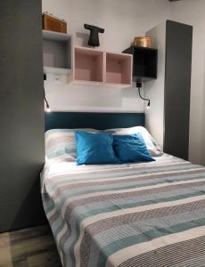 a bedroom with a bed with a blue pillow and shelves at La Casita: Studio cosy indépendant de 25 m² in Les Sables-d'Olonne