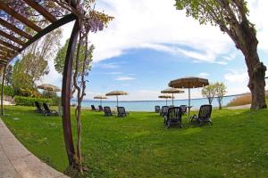 un grupo de sillas y mesas con sombrillas en el césped en Hotel Smeraldo, en Sirmione