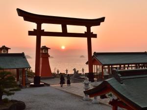 a torii gate in front of the ocean at sunset at Sky Heart Hotel Shimonoseki in Shimonoseki