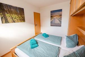 2 Betten in einem Zimmer mit blauen Kissen in der Unterkunft Weg App 2 in Norderney