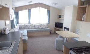 a kitchen and living room with a couch and a window at 8 Berth Caravan With Decking At Caister Beach In Norfolk Ref 30016s in Great Yarmouth