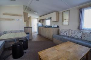 a living room with a couch and a table at 8 Berth Caravan With Decking At Caister Beach In Norfolk Ref 30016s in Great Yarmouth