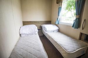 2 camas en una habitación pequeña con ventana en Superb 8 Berth Caravan At Caister Beach In Norfolk Ref 30073f en Great Yarmouth