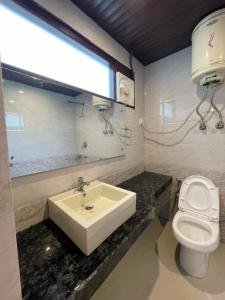ein Bad mit einem Waschbecken, einem WC und einem Fenster in der Unterkunft The Royal Majestic Mountain View in Manali