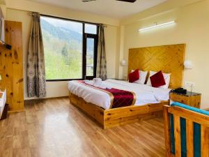 a bedroom with a bed and a large window at The Royal Majestic Mountain View in Manāli