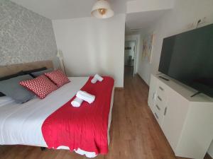 a bedroom with a bed with a red blanket and a flat screen tv at EL ÚNICO apartment with jacuzzi and art in Guadalest