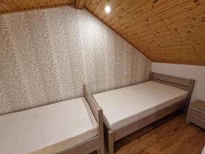 Habitación pequeña con 2 camas y techos de madera. en Domek Mazurski Chill, en Jakubowo