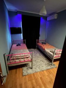 two twin beds in a room with purple lighting at Skytrack SA in Thessaloniki