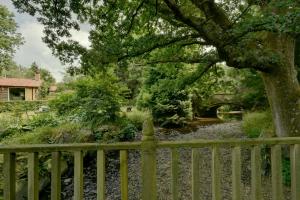 a wooden fence next to a river with a bridge at Bradford Mill in Tiverton