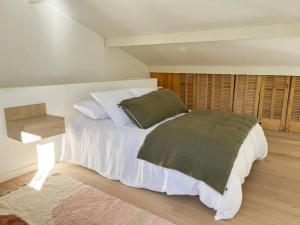- une chambre dotée d'un grand lit avec des draps blancs et des oreillers verts dans l'établissement Jolie villa à quelques pas du centre-ville., à Nîmes