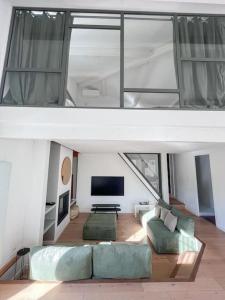 sala de estar con sofá y TV en Jolie villa à quelques pas du centre-ville. en Nimes