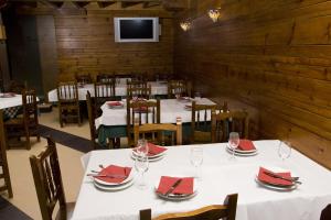 un comedor con mesas blancas y sillas con servilletas rojas en Hotel Restaurante Prado, en Boal