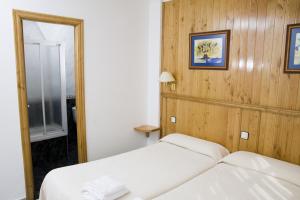 1 dormitorio con cama blanca y espejo en Hotel Restaurante Prado, en Boal