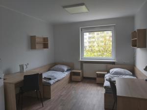 Cette chambre comprend 2 lits, une table et une fenêtre. dans l'établissement Dom Studencki Komenik, à Leszno