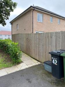 a fence and a trash can in front of a house at Very Close to Chester City Centre! in Christleton
