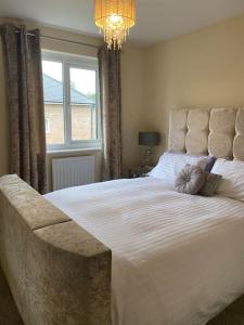 a bedroom with a large white bed and a chandelier at Very Close to Chester City Centre! in Christleton