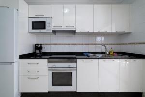 a white kitchen with white cabinets and a sink at Apartamento Sussa 7C by HH in Los Pocillos +9 photos