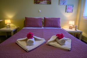 Una cama púrpura con toallas y flores. en Pavlina's Apartments 1, en Chrani