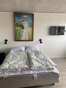 a bed in a room with a painting on the wall at JJ Guesthouse Studio 37 in Skagen