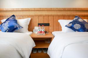 two beds with blue and white pillows and drinks on a table at 武陵山水客栈Wuling Shanshui Hotel in Zhangjiajie