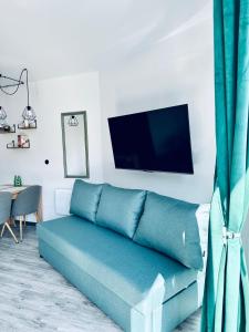 un canapé bleu dans un salon avec une télévision à écran plat dans l'établissement AL-DOM Apartamenty Apartament 103, à Kołobrzeg