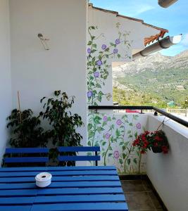 un balcón con bancos azules y una pared con flores en EL ÚNICO apartment with jacuzzi and art en Guadalest