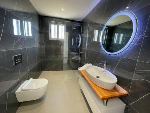 bagno con lavandino, servizi igienici e specchio di Helen's Seaside Resort a Sarandë