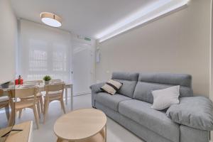 Sala de estar con sofá gris y mesa en Apartamentos Pamplona Confort by Clabao, en Pamplona