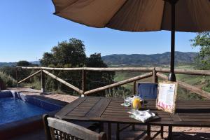 a wooden table with an umbrella and a drink on it at Casa KiSi Cottage, Rural Boutique Bed & Breakfast in Málaga
