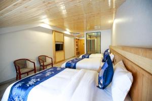 a bedroom with two beds and two chairs at 武陵山水客栈Wuling Shanshui Hotel in Zhangjiajie