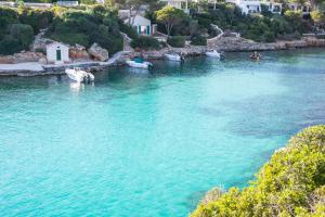 una gran masa de agua con barcos dentro en Pierre & Vacances Menorca Cala Blanes, en Cala en Blanes