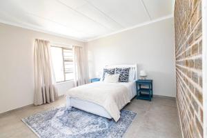 a white bedroom with a bed and a window at Ocean Views, 50m from the beach! in East London