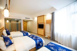 a hotel room with two beds and a television at 武陵山水客栈Wuling Shanshui Hotel in Zhangjiajie
