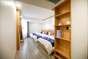 a room with three beds and a tv in it at 武陵山水客栈Wuling Shanshui Hotel in Zhangjiajie