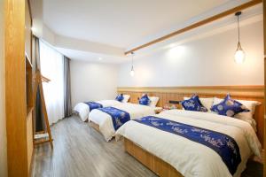 three beds in a room with blue and white sheets at 武陵山水客栈Wuling Shanshui Hotel in Zhangjiajie