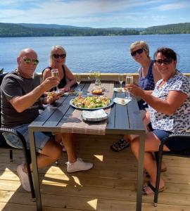 un grupo de personas sentadas alrededor de una mesa con copas de vino en Snibben Höga Kusten en Ramvik
