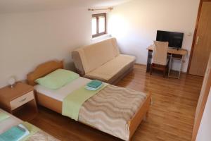 Rooms Marija - rooms with pool في Trilj: غرفة نوم صغيرة مع سرير وأريكة