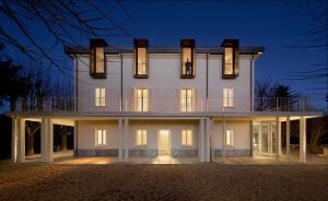 una gran casa blanca por la noche con luces encendidas en Villa Trisano, en Bra